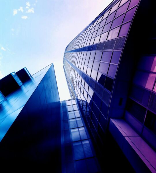 Modern blue-purple glass skyscraper facade with geometric reflections — Valukoda True CISO enterprise scale